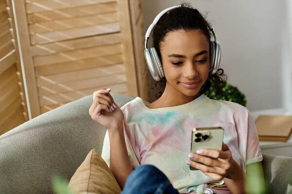 Женщина, погруженная в музыку по телефону, сидя на диване.