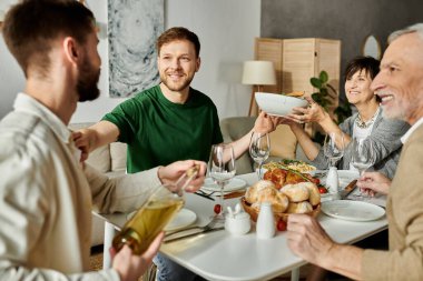 Eşcinsel bir çift evde aileleriyle yemek yiyor ve şenlikli bir toplantının tadını çıkarıyor..