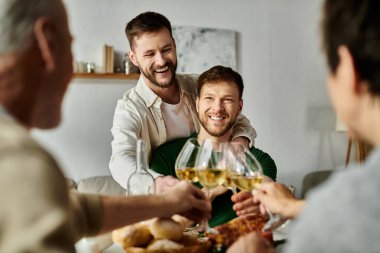 A gay couple toasts with their family, celebrating together in a home setting. clipart