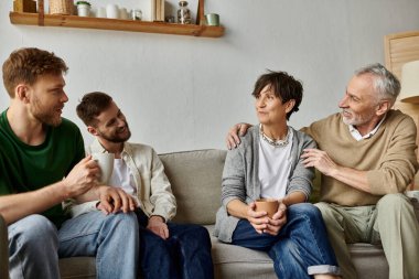 A gay couple shares a conversation with parents in a comfortable living room. clipart