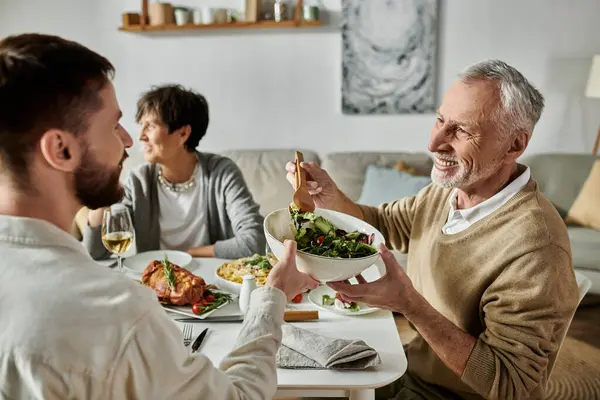 stock image A gay couple shares a meal with parents at home.