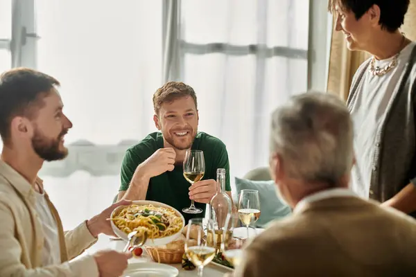 Stock image A gay couple enjoys dinner with parents at home, creating warm memories.