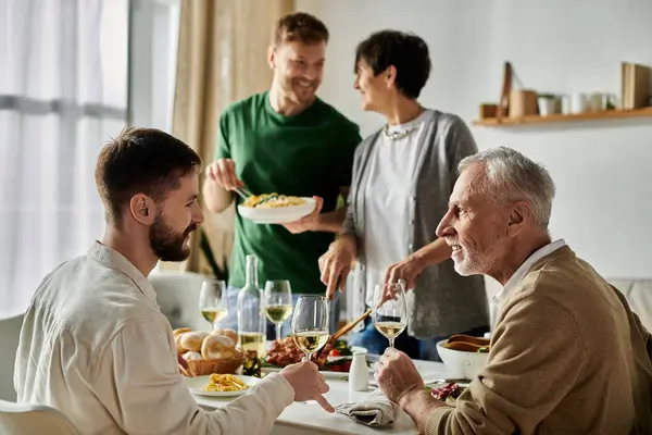 stock image A gay couple shares a meal with parents, enjoying a moment of connection and love.