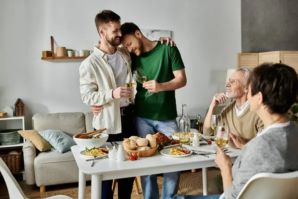 stock image A gay couple stands together, arms around each other, while introducing their partner to their family during a celebratory dinner at home.