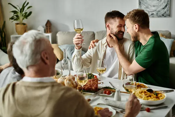 stock image A gay couple shares a loving moment while dining with their family at home.