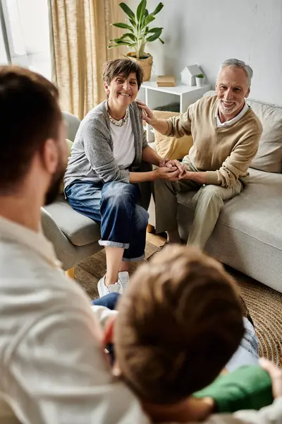 stock image A gay couple sits with parents in a living room, enjoying a warm and loving moment together.