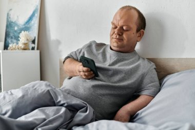 Kapsamlı bir adam yatakta, akıllı telefonunu kullanarak güne başlıyor..