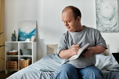 A man with inclusivity sits on a bed, thoughtfully writing in a notebook. clipart