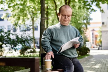 Kapsayıcı bir adam parkta bir bankta oturur, gazete okur ve bir fincan kahvenin tadını çıkarır..