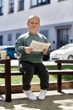 Kapsamlı bir adam, güneşli bir günde kentteki bir bankta oturup gazete okur..
