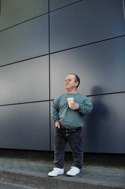 A man with inclusivity stands in front of a building, holding a cup of coffee. clipart