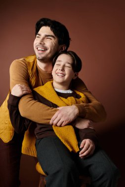 Bir baba ve oğul sıcacık bir kucaklaşmayı paylaşır, neşe ve kahkaha ile parlarlar..