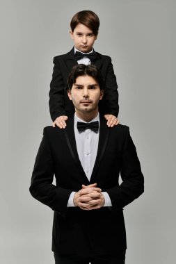 Takım elbiseli bir baba ve oğul babasının omuzlarında oturuyor..