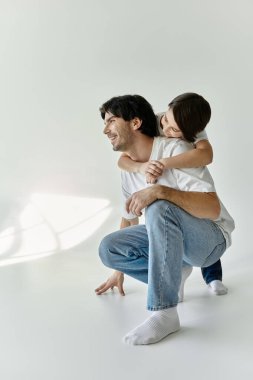 Bir baba ve oğlu yerde oturup, bağlarının mutluluğunu kucaklarken aynı kahkahayı paylaşıyorlar..