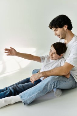 Bir baba ve oğlu yerde oturuyor, gülüyor ve birbirlerine eşlik ediyorlar..