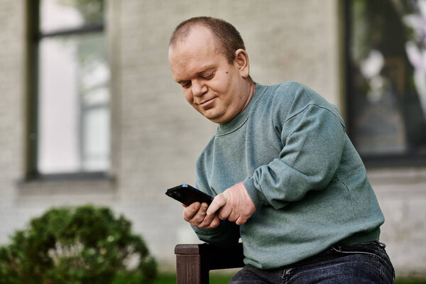 A man with inclusivity sits on a bench and uses his smartphone while smiling.