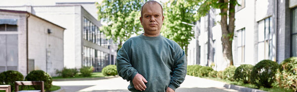 Человек с инклюзивностью стоит на городской улице, глядя вперед с решительным выражением.