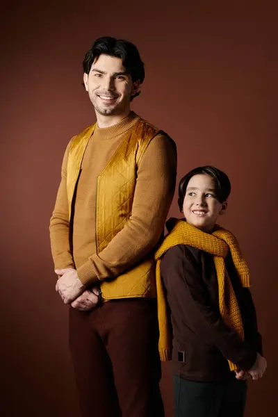 stock image A father and son stand side-by-side, smiling at the camera.