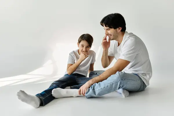 stock image A father and son sit on the floor, laughing together.