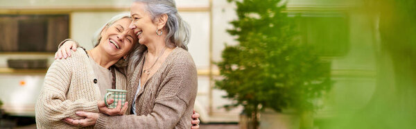 A lesbian couple smiles and embraces while camping in the forest near their van.