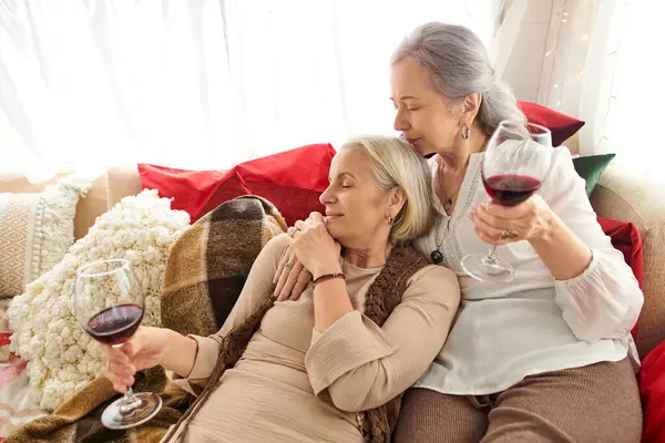 stock image A lesbian couple relaxes on a comfy couch inside their camper van while enjoying a glass of red wine.