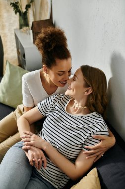 Lezbiyen bir çift evlerinde kanepede birbirlerine sarılırlar..