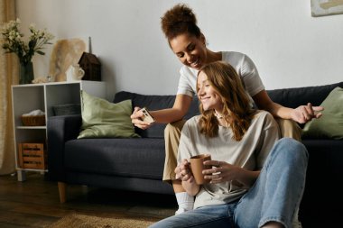 A lesbian couple shares a laugh while enjoying a cozy afternoon at home. clipart