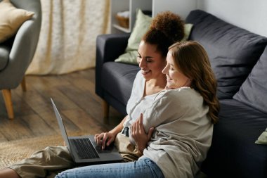 Lezbiyen bir çift evde oturup dizüstü bilgisayarlarında paylaştıkları anın tadını çıkarıyor..