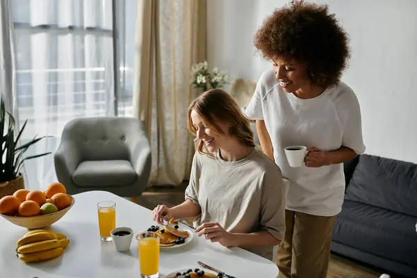 stock image A lesbian couple enjoys a casual breakfast at home, sharing a smile and a cup of coffee.