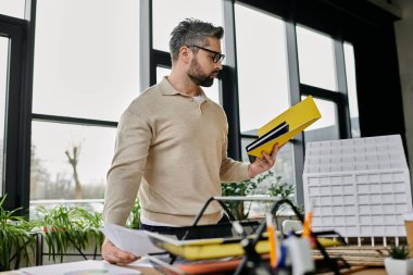 Modern ofis ortamında, masasında özenle çalışan yakışıklı sakallı bir iş adamı..