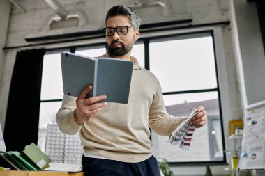 Sakallı yakışıklı bir işadamı modern ofis ortamındaki renk örneklerini inceliyor..