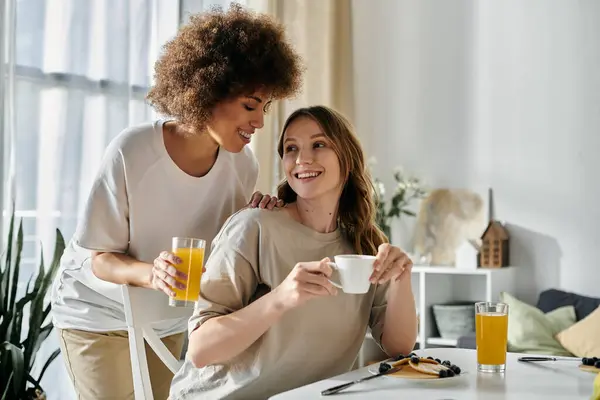 stock image Two women share a tender moment at home while enjoying their breakfast.