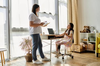 A brunette mother and her daughter, who has a prosthetic leg, spend time at home. clipart