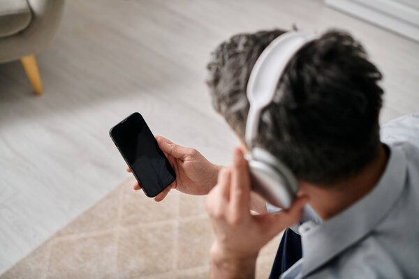 man wearing headphones and holding his smartphone.