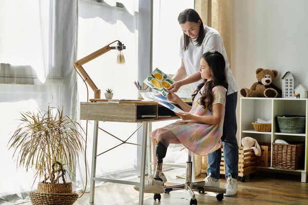 A brunette mother and her daughter with a prosthetic leg spend quality time together at home, drawing and enjoying each others company.