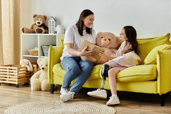 A mother and her daughter are sitting on a yellow sofa, reading a book together. The daughter has a prosthetic leg.