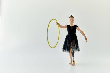 A young girl with a prosthetic leg performs a gymnastics routine with a hula hoop. clipart