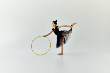 A young girl with a prosthetic leg practices gymnastics with a hula hoop. clipart