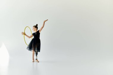 A young gymnast with a prosthetic leg performs a graceful hoop routine in a studio setting. clipart