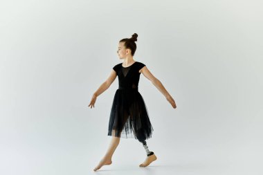 Protez bacaklı genç bir kız beyaz bir stüdyoda zarif bir jimnastik gösterisi yapıyor..