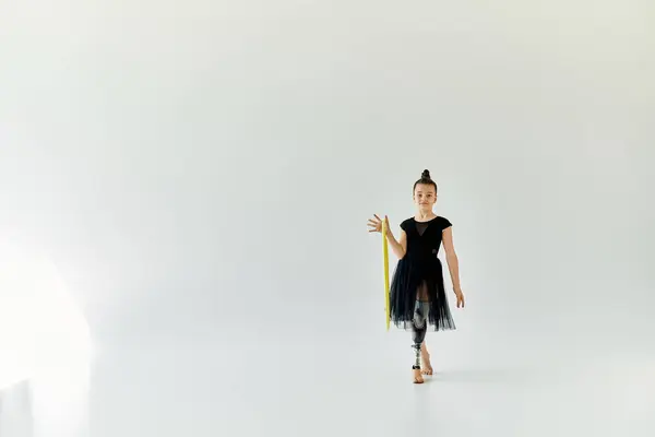 stock image A young girl with a prosthetic leg practices gymnastics with a yellow hoop in a white studio.