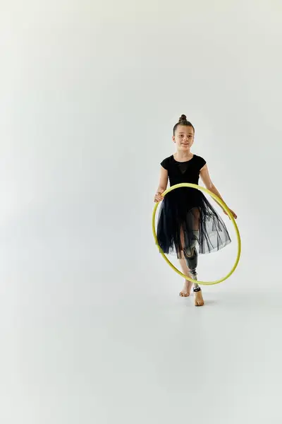 stock image A young girl with a prosthetic leg is spinning a hula hoop in a studio.