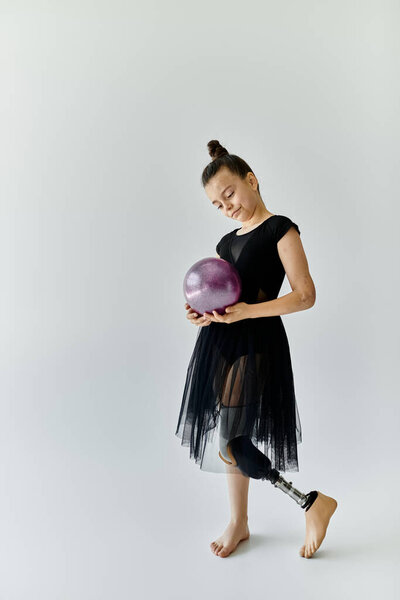 Молодая девушка с протезной ногой практикует гимнастику с фиолетовым мячом..