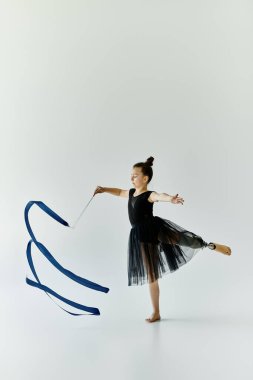 Protez bacaklı genç bir kız mavi kurdeleli ritmik jimnastik gösterisi yapıyor..