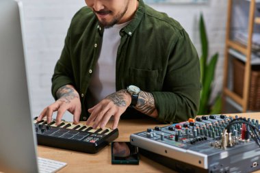 A handsome Asian man plays a MIDI keyboard in his studio. clipart