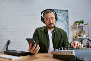 Sıradan yeşil tişörtlü, kulaklık takan yakışıklı bir Asyalı stüdyoda müzik yapıyor..