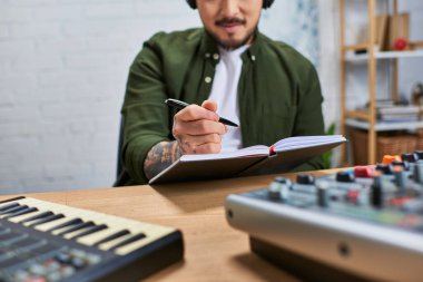 Sıradan kıyafetler giyen Asyalı bir adam yeni bir müzik stüdyosunda çalışıyor..