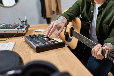 Yakışıklı Asyalı bir adam bir müzik stüdyosunda elektrikli klavye ve akustik gitar çalıyor..