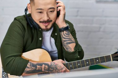 Yakışıklı bir Asyalı kayıt stüdyosunda gitar çalıyor..