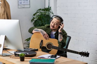Çok enstrümanlı bir Asyalı adam atölyesinde çalışırken görülüyor. Akustik gitar çalıyor ve kulaklıkla müzik dinliyor..